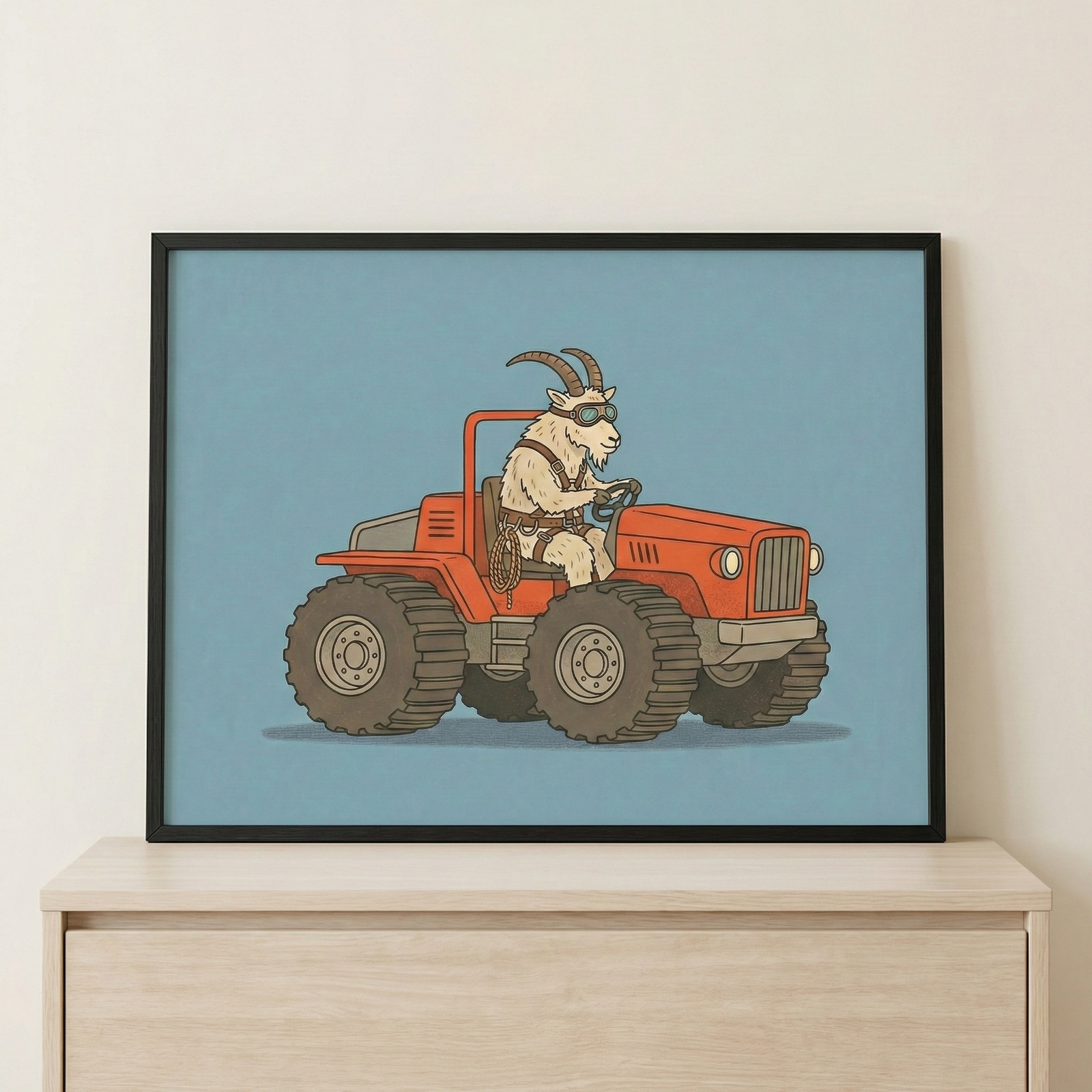 Framed wall art featuring an animal goat wearing goggles and driving an orange car, sitting on a light-colored wooden cabinet against a plain white wall.