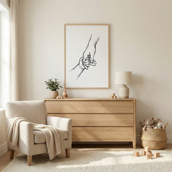 Minimalist parent hand holding hands with a child wall art hanging above a light wood dresser in a cozy nursery.