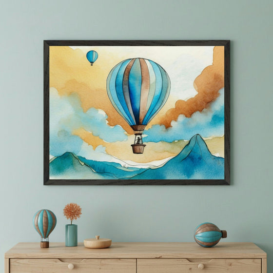 Modern room with a light wood dresser. A framed watercolor painting of a blue and brown hot air balloon, mountains, and yellow-orange sky hangs centered above the dresser. Decorative hot air balloons, a vase, and a wooden bowl are on the dresser.