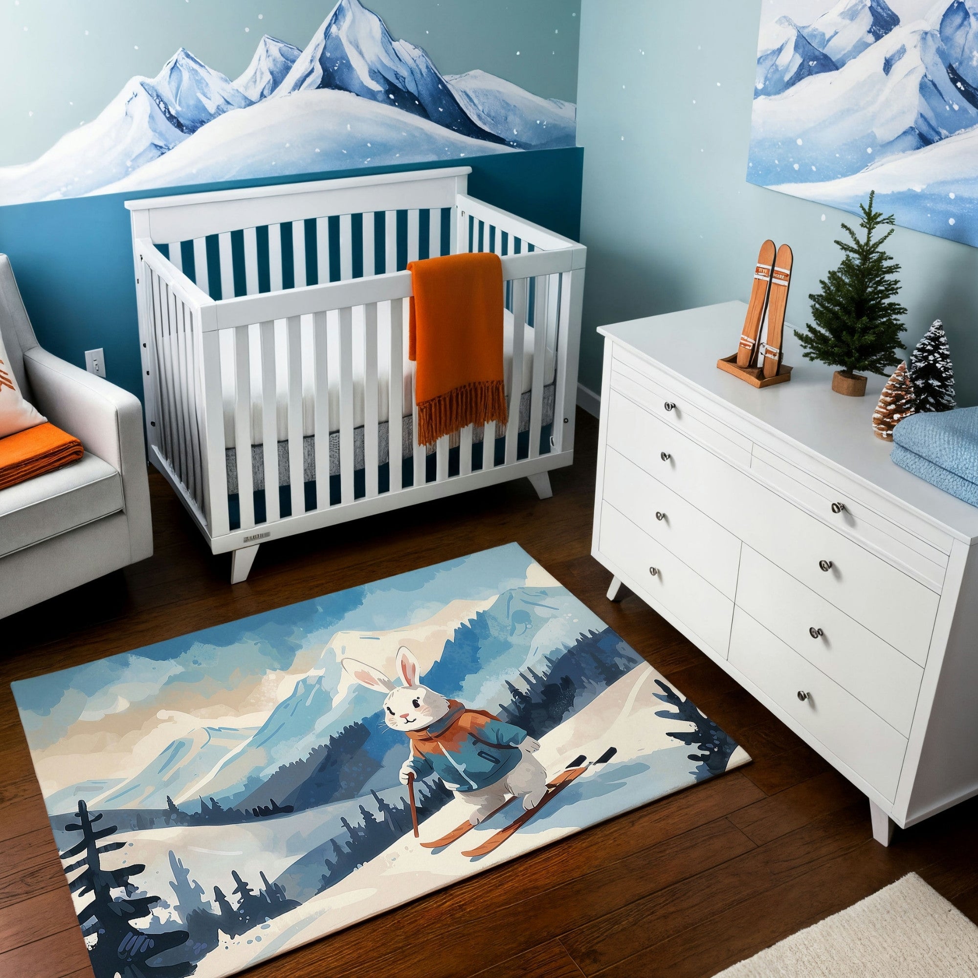 A winter-themed nursery featuring a white crib with an orange blanket, a white dresser, and a cozy armchair with orange accents. The walls are decorated with a snowy mountain mural, and the dresser is adorned with miniature skis and a small pine tree. A vibrant area rug showcases a skiing bunny dressed in winter gear, set in a snowy mountain landscape, adding a playful and seasonal touch to the space.