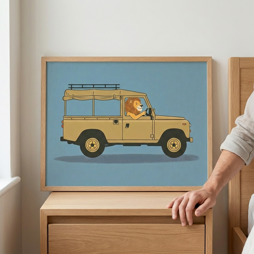 Framed wall art featuring a lion driving a tan vehicle car, held by a hand in a light wood frame against a white wall.
