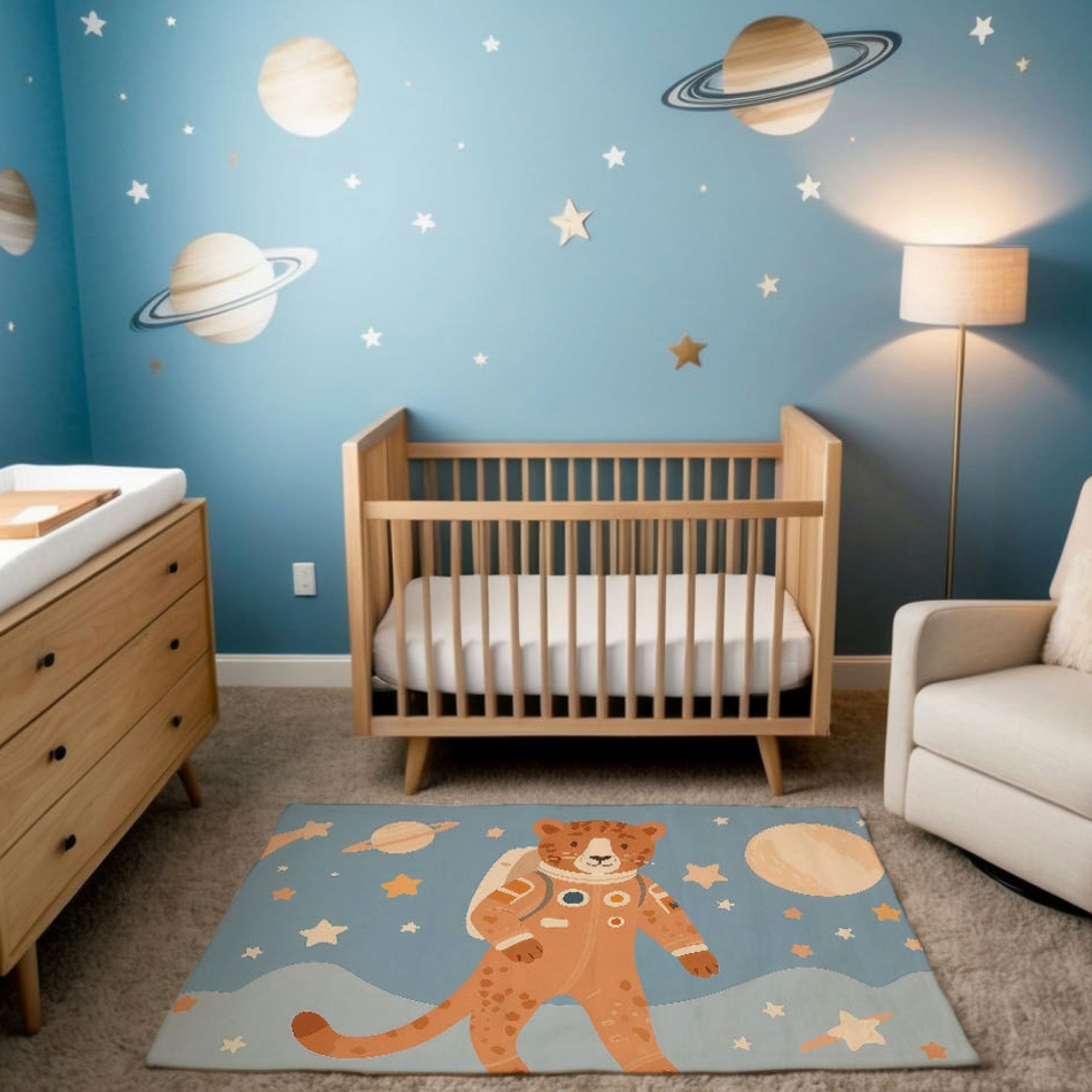 A space-themed nursery featuring a natural wood crib, light wood dresser, and walls painted blue with illustrations of planets, stars, and moons. The room includes a cozy cream armchair and a rug depicting a whimsical illustration of a cheetah in a spacesuit, standing on a stylized planetary surface surrounded by stars and planets.