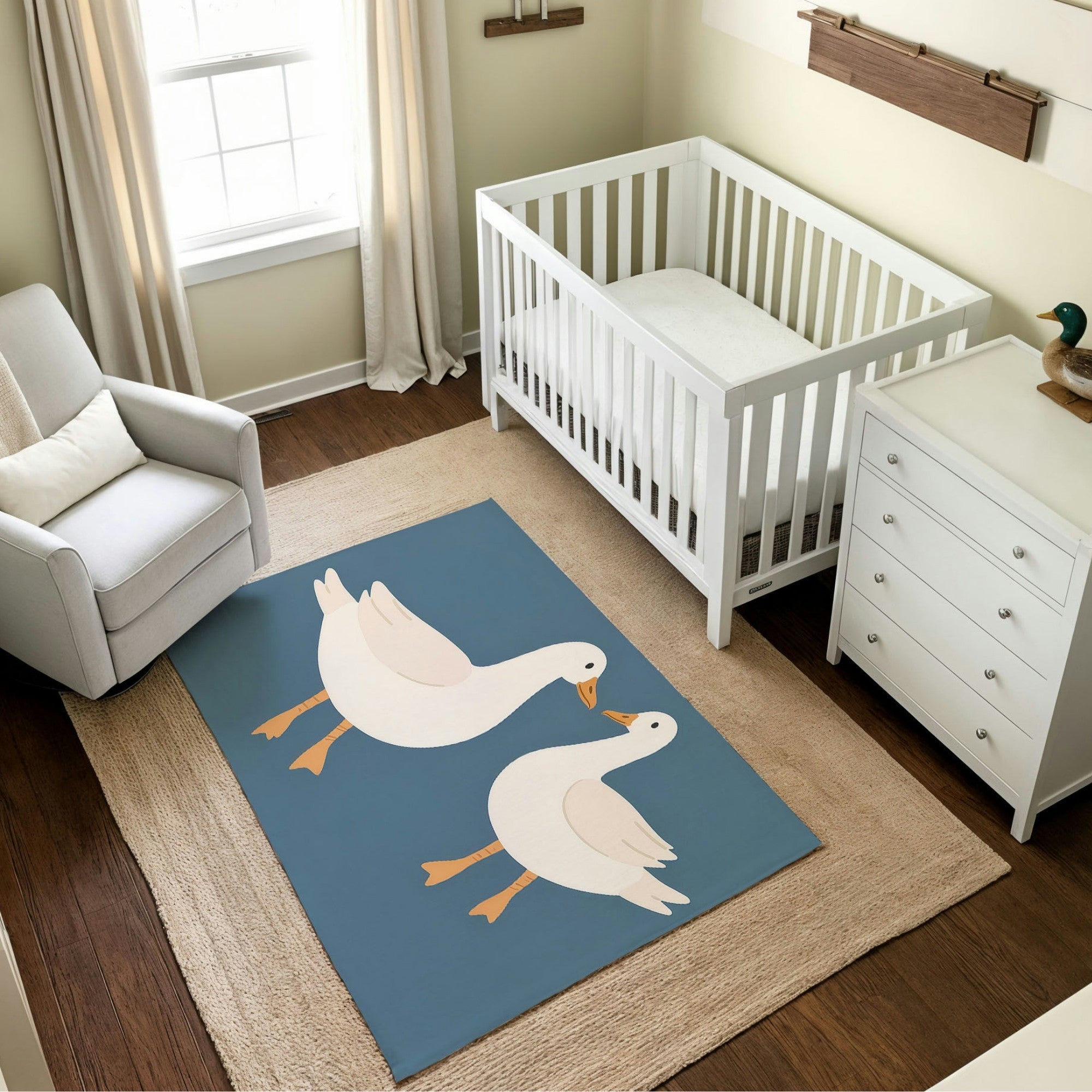 A bright and cheerful nursery featuring a white crib and dresser set against soft cream-colored walls with wooden accent shelves. The room includes a gray armchair with a pillow, light curtains, and a large beige rug. The centerpiece is a blue rug with an illustration of two white geese standing side by side, adding a playful and pastoral charm to the space.