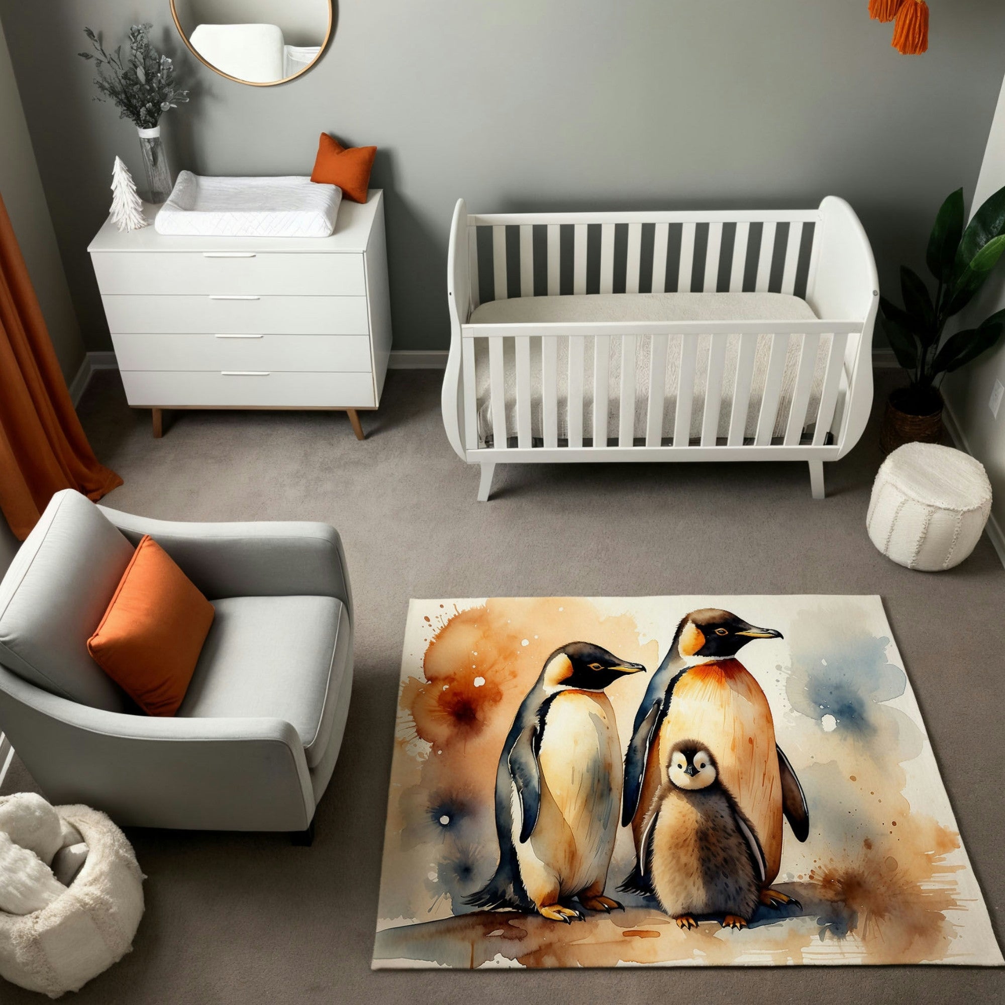 A modern nursery featuring a white crib and dresser, set against soft gray walls, with orange accents in the decor adding a pop of color. The room includes a cozy gray armchair, a white pouf, and a round mirror above the dresser. The centerpiece is a watercolor-style rug depicting a family of penguins—two adults and a fluffy chick—surrounded by splashes of blue, orange, and earthy tones, creating a serene and artistic focal point.