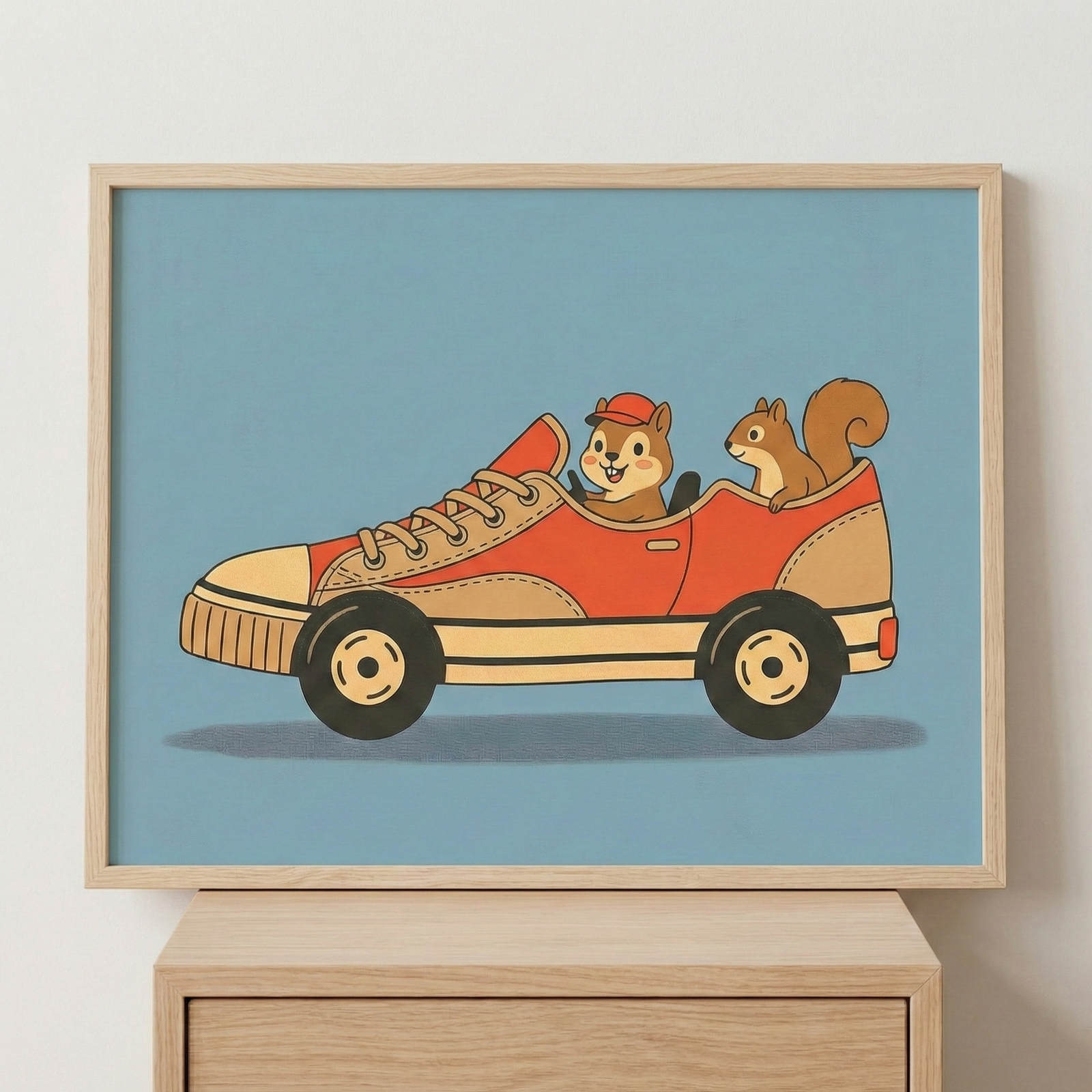 Framed wall art of a squirrel and another rodent driving a sneaker-shaped car, displayed on a wall above a wooden dresser.