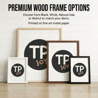 Four framed art prints leaning against a wall, each featuring the logo “TP JOY” in bold white and tan letters on a black circle, displayed in premium wood frames in white, natural oak, walnut, and black. Text above highlights the frame color options and mentions that prints are on fine art matte paper.