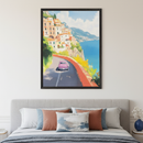 Modern bedroom with a light gray upholstered bed. A framed painting of a pink car on a coastal road with white and orange houses, green hills, and a blue ocean hangs centered above the bed. The art has a painterly style.
