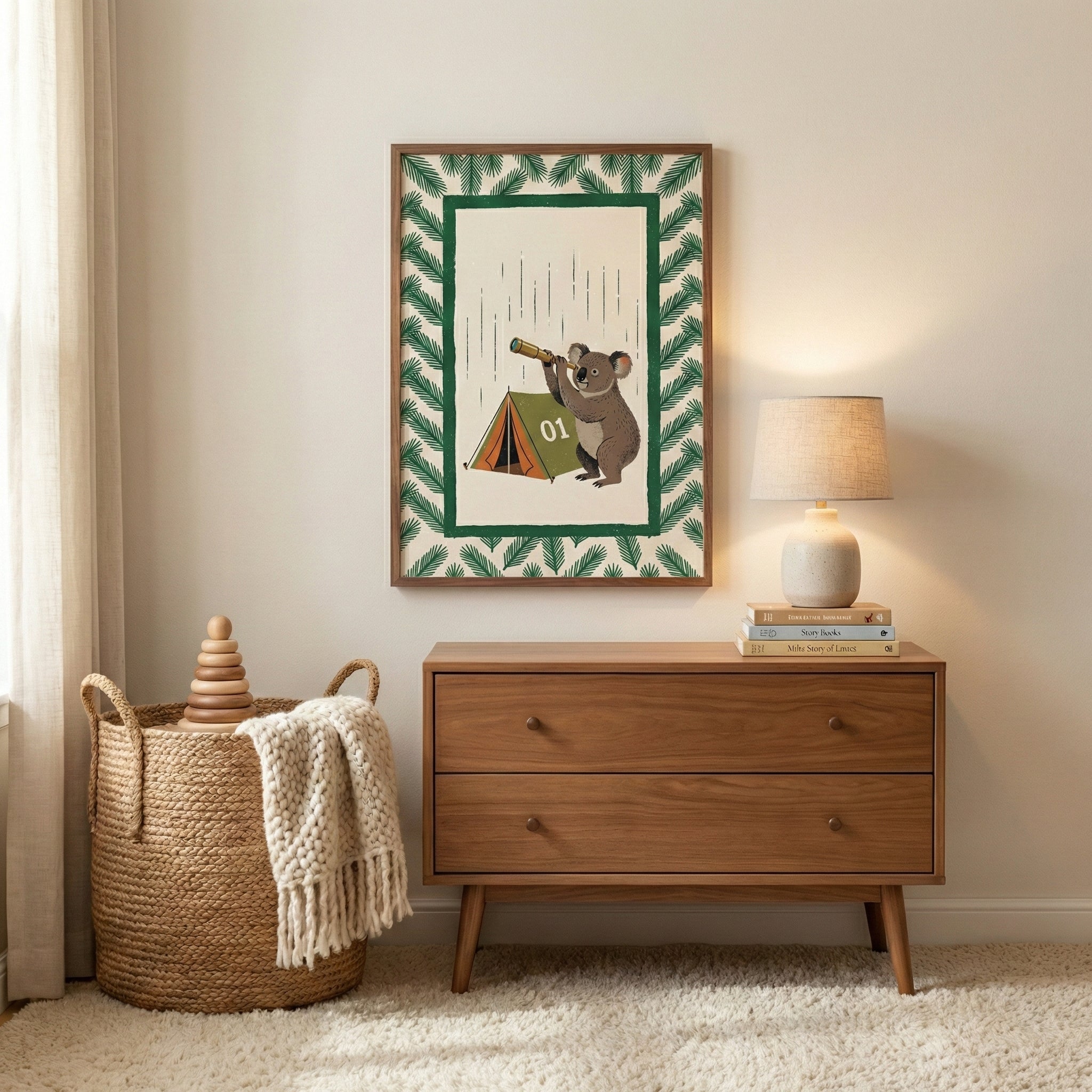 A cozy, neutral-toned room featuring a mid-century modern wooden dresser. Atop the dresser sits a stack of books and a lamp with a textured base and a simple drum shade, casting a warm glow. Hanging on the wall above the dresser is a framed illustration depicting a cartoon koala peering through a telescope next to a small green tent marked "01" under vertical lines representing rain, all surrounded by a border of green foliage. 