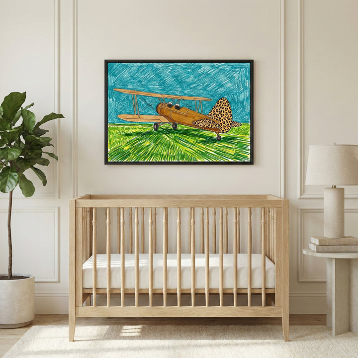 A framed drawing of a vintage biplane airplane with a leopard print tail hangs on the wall above a wooden baby crib in a softly lit nursery. The artwork features bold colors with green grass and a blue sky, adding a playful aviation theme to the room.