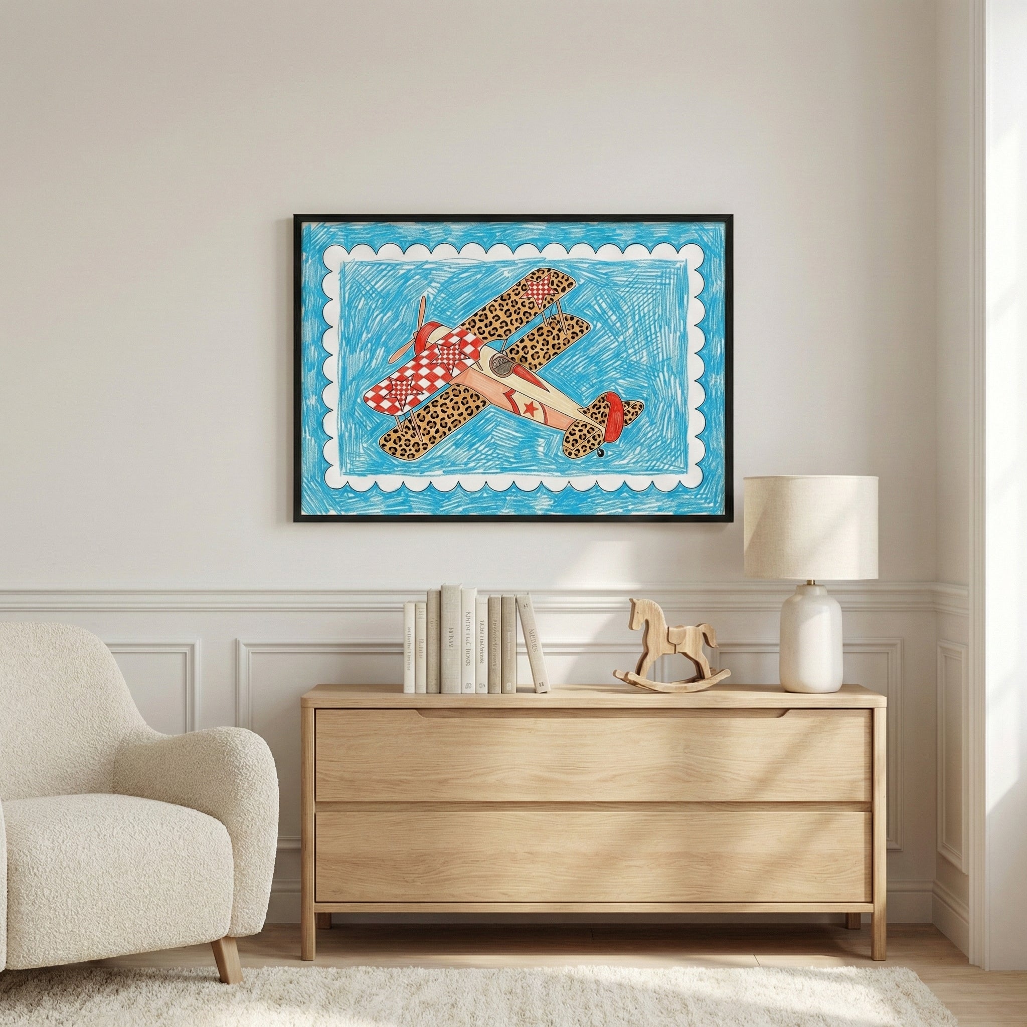 Framed artwork of a whimsical leopard-print and red checkered biplane airplane hangs above a light wood dresser in a cozy, modern room with neutral decor and a plush armchair.