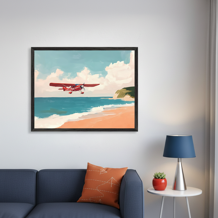 Modern living room with a dark blue sofa. A large framed painting of a red airplane flying over a sandy beach with blue water and a green cliff hangs above the sofa. A side table with a blue lamp is to the right.
