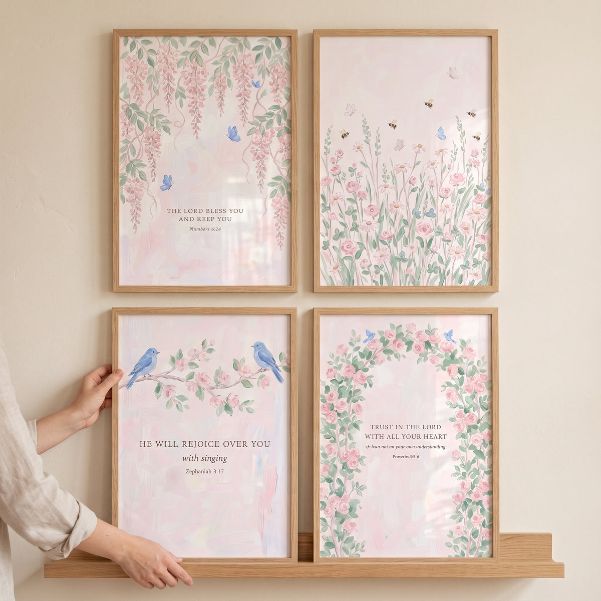 Airy blush pink garden wall art set of 4 featuring floral designs and birds in light wood frames on a neutral wall.