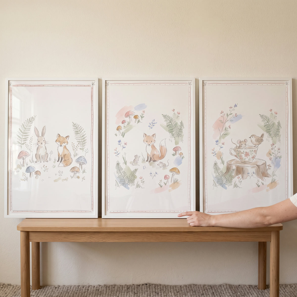 An airy charming woodland animals wall art set of 3 watercolor prints of foxes and rabbits on a light wooden bench.