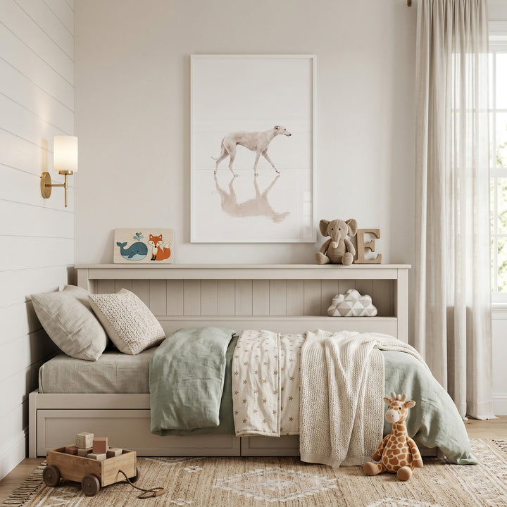Neutral bedroom featuring airy coastal walking dog wall art, a bed with plush toys, and a wooden toy cart.