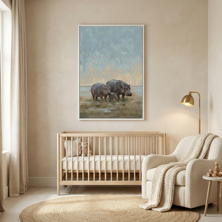 A neutral-toned nursery with a minimalist design. A large framed artwork of a hippo family—two adults and a calf—in a soft, atmospheric landscape hangs on a beige wall. Below the art is a light wood crib with a small plush bear. To the right, a cream-colored armchair is draped with a textured knit throw, placed next to a gold floor lamp. A large circular woven rug sits on the floor, and light-colored curtains hang by the window.