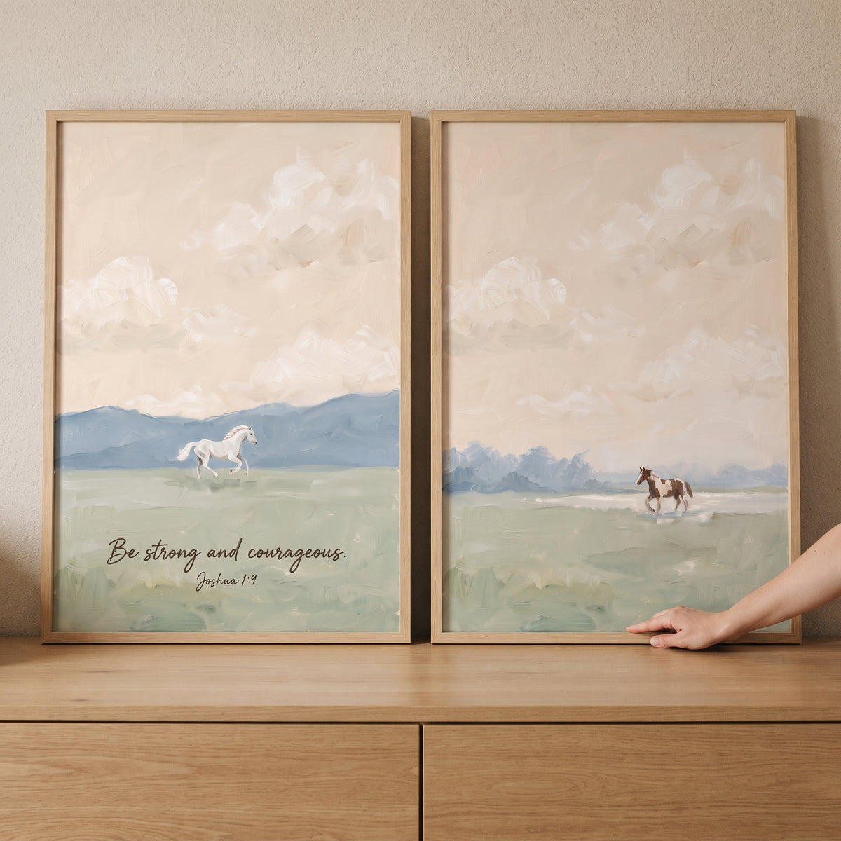 Apricot sunset meadow horse wall art set of 2 with horses and scripture over soft blue hills on a wood cabinet.