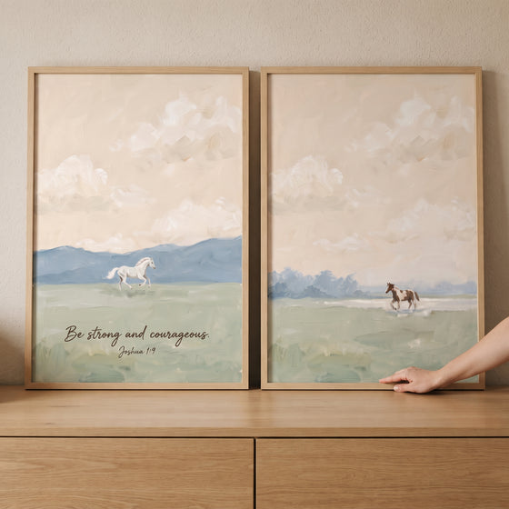 Apricot sunset meadow horse wall art set of 2 with horses and scripture over soft blue hills on a wood cabinet.