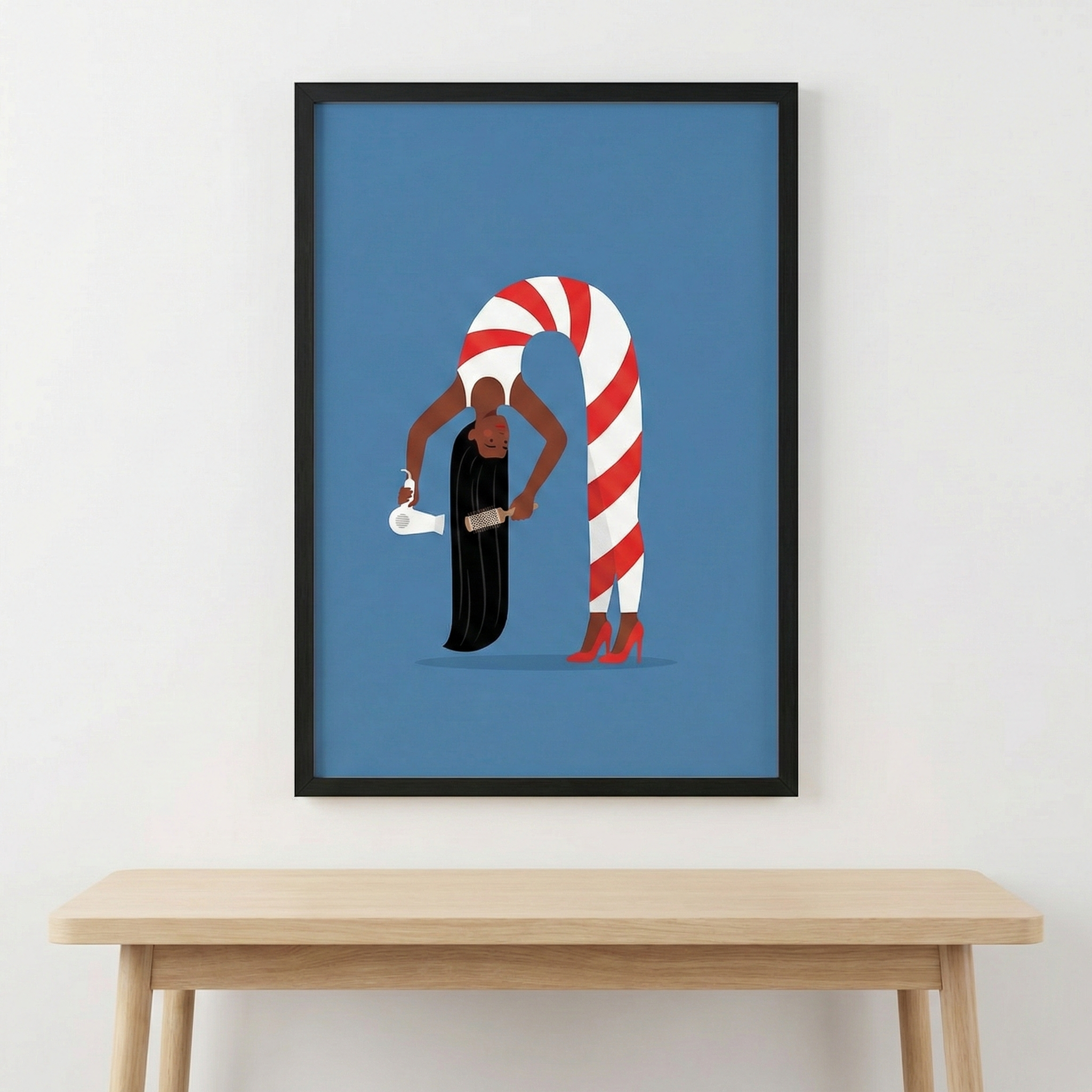 A framed digital illustration hangs on a plain white wall above a light wood table. The artwork features a woman with dark skin and long, straight black hair against a solid blue background. She is depicted in a flexible, arched pose, bending forward with her head hanging down. She wears a form-fitting, red and white diagonally striped unitard and red high-heeled pumps. In one hand, she holds a white hair dryer, while the other hand uses a brush on her long hair.