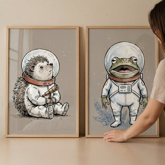 Astronaut animal wall art set of 2 featuring a hedgehog and a frog in white spacesuits within light wood frames.