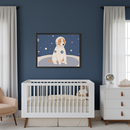 Modern nursery with dark blue walls. A white crib is centered, with a beige armchair to its left and a white dresser to its right. Above the crib, a framed cartoon print depicts a dog in an astronaut suit on a starry, dark blue background.