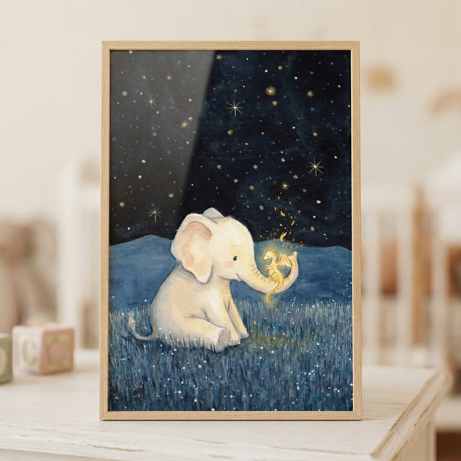 A whimsical illustration of a small, cream-colored baby elephant sitting in a field of dark blue grass. Perched on the end of the elephant's trunk is a tiny, glowing golden dragon that appears to be emitting small magical sparks. The scene is set under a vast, dark blue night sky filled with many twinkling stars of various sizes. In the mid-ground, there's a dark blue silhouette of rolling hills. The artwork has a soft, gentle aesthetic, characteristic of a children's storybook.