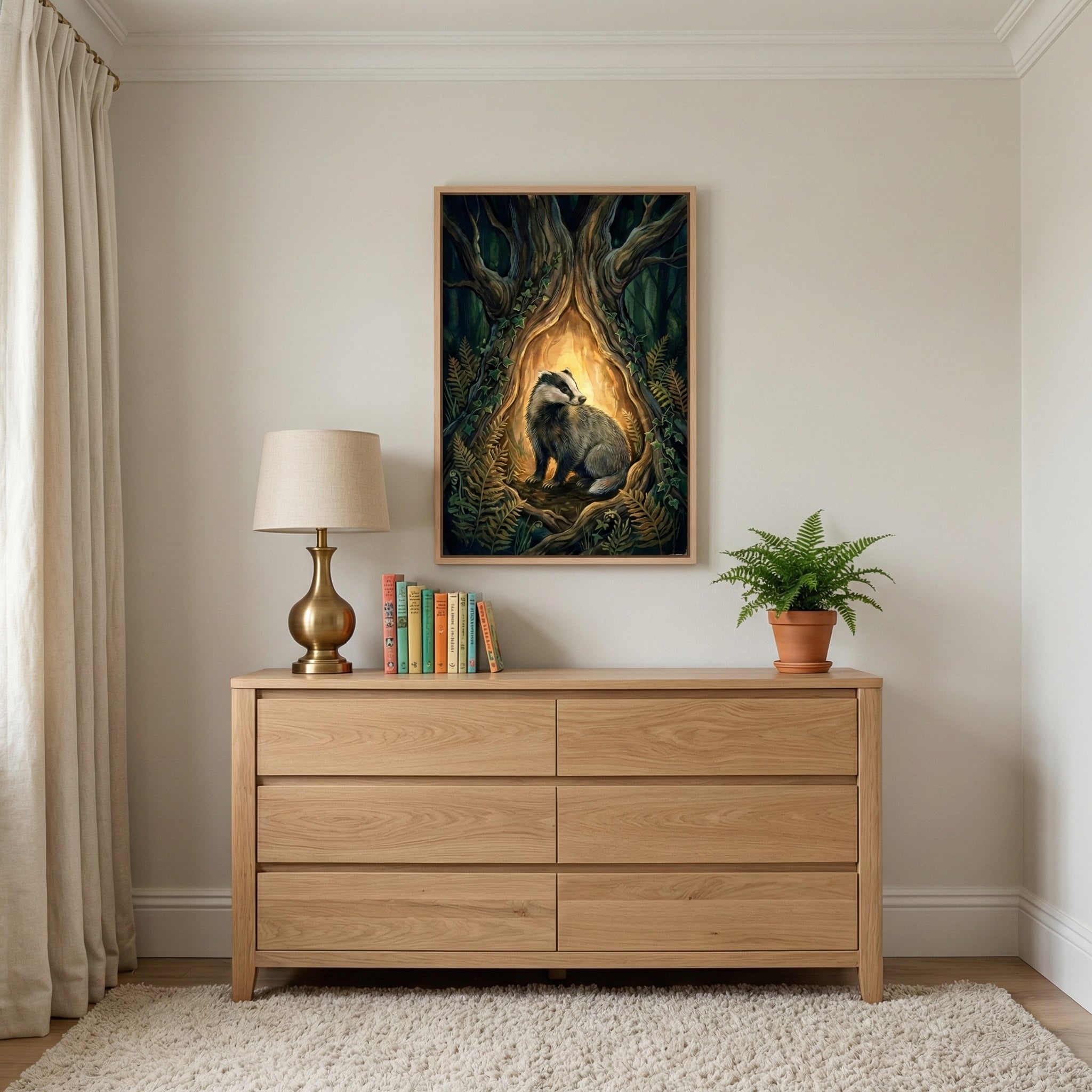 Framed badger painting hung above a natural wood dresser in a softly lit, minimalist room. The artwork's glowing forest setting adds a sense of warmth and quiet strength to the space.
