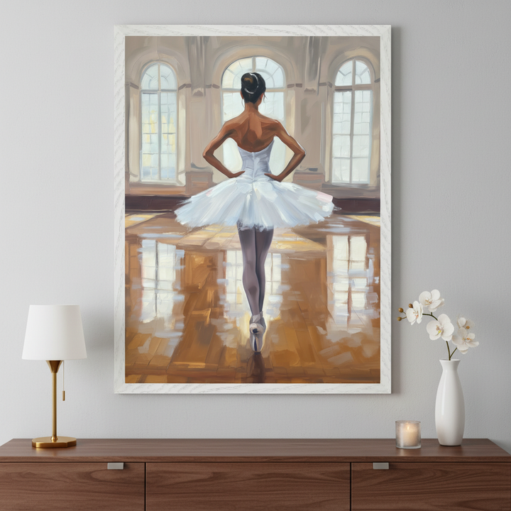 Modern room with a dark wooden dresser. A large framed painting of a dark-skinned ballerina in a white tutu, seen from behind in a brightly lit room with arched windows, hangs centered above the dresser. A lamp, candle, and white orchid vase are on the dresser.