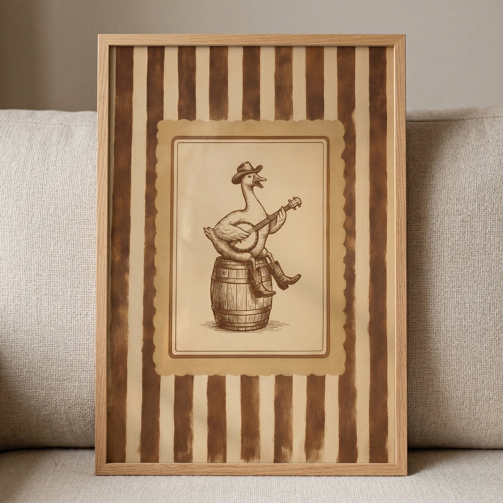 Framed banjo playing cowboy goose wall art shows a bird in boots on a barrel against vertical brown and tan stripes.