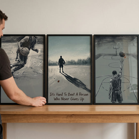 Man displays a basketball player sports wall art set of 3 with monochrome sketches of athletes on a wooden shelf.