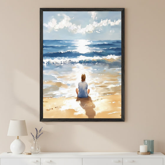 Modern room with a white dresser. A large black-framed painting of a person sitting on a sunny beach looking at the ocean hangs centered above the dresser. The art shows bright sunlight reflecting on the water and sand in a painterly style.