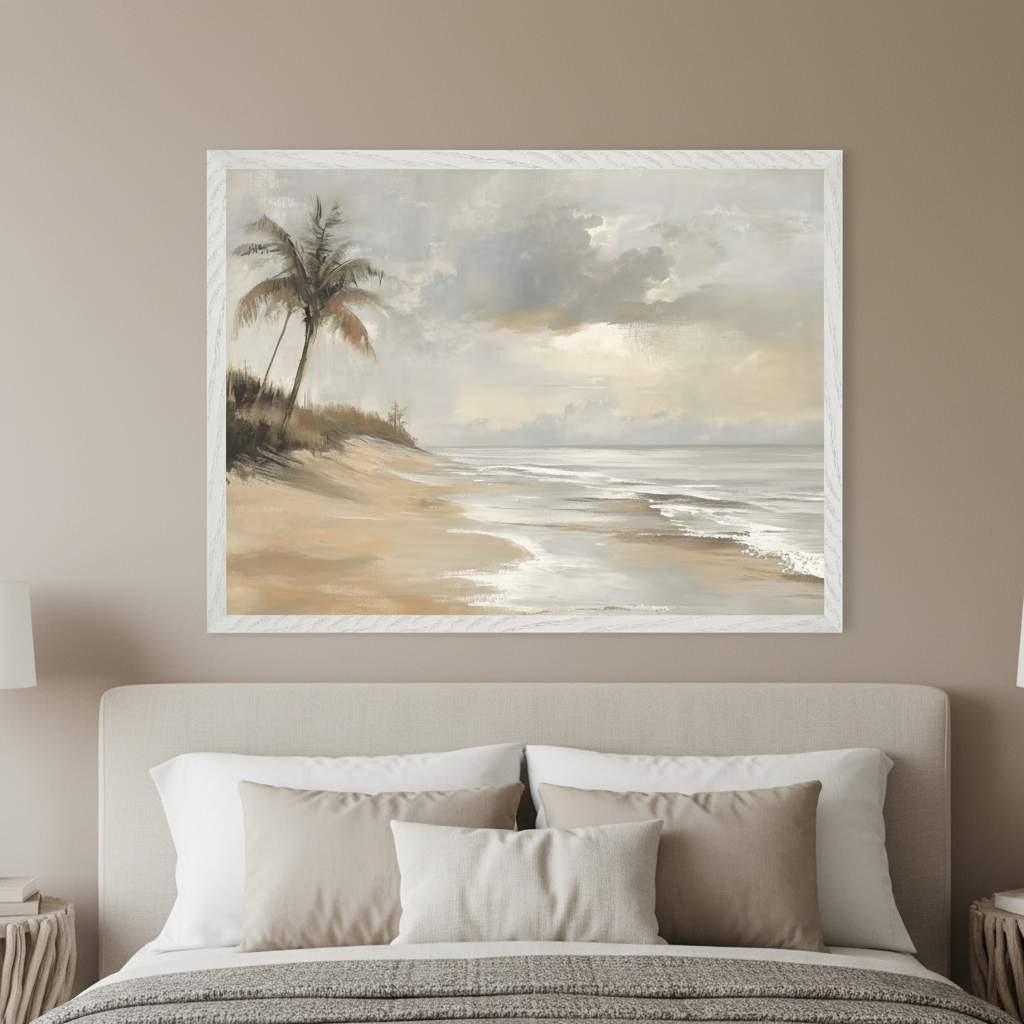 Modern bedroom with a beige upholstered bed. A large framed painting of a beach scene with palm trees on sand dunes, gentle waves, and a cloudy sky hangs centered above the bed. The art has a soft, muted color palette.