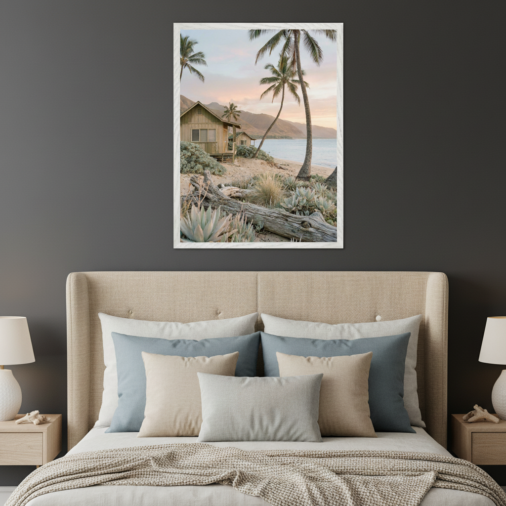 Bedroom with a beige upholstered bed and nightstands. A large framed vertical print of a tropical beach with cabins, palm trees, sand, succulents, and ocean at sunset hangs centered above the bed.