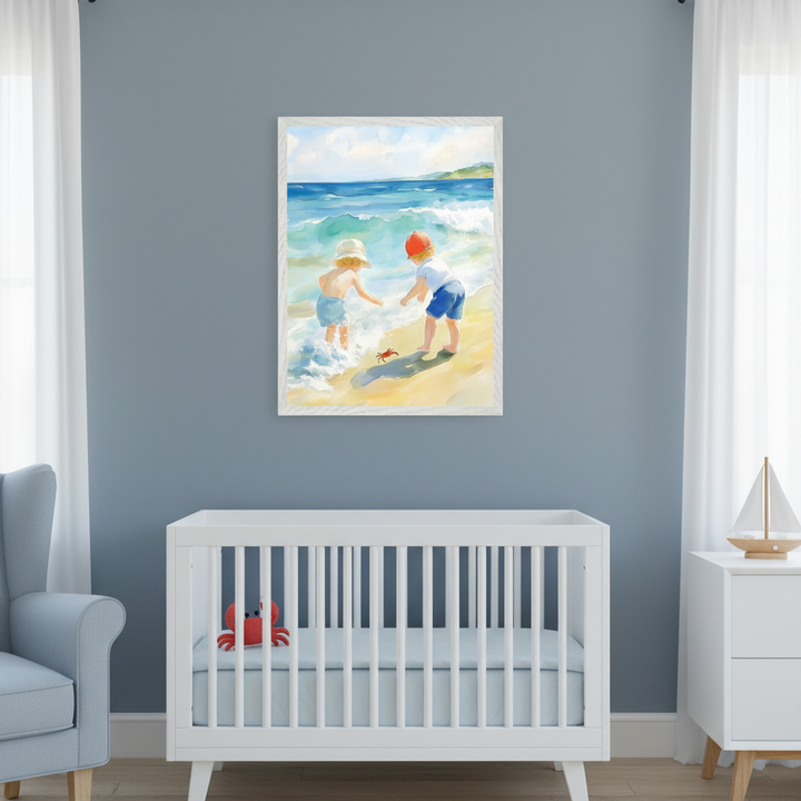 Modern nursery with a blue-gray wall. Above a white crib, a framed watercolor painting depicts two kids playing with a red crab on a sandy beach. A light blue armchair and white dresser flank the crib.