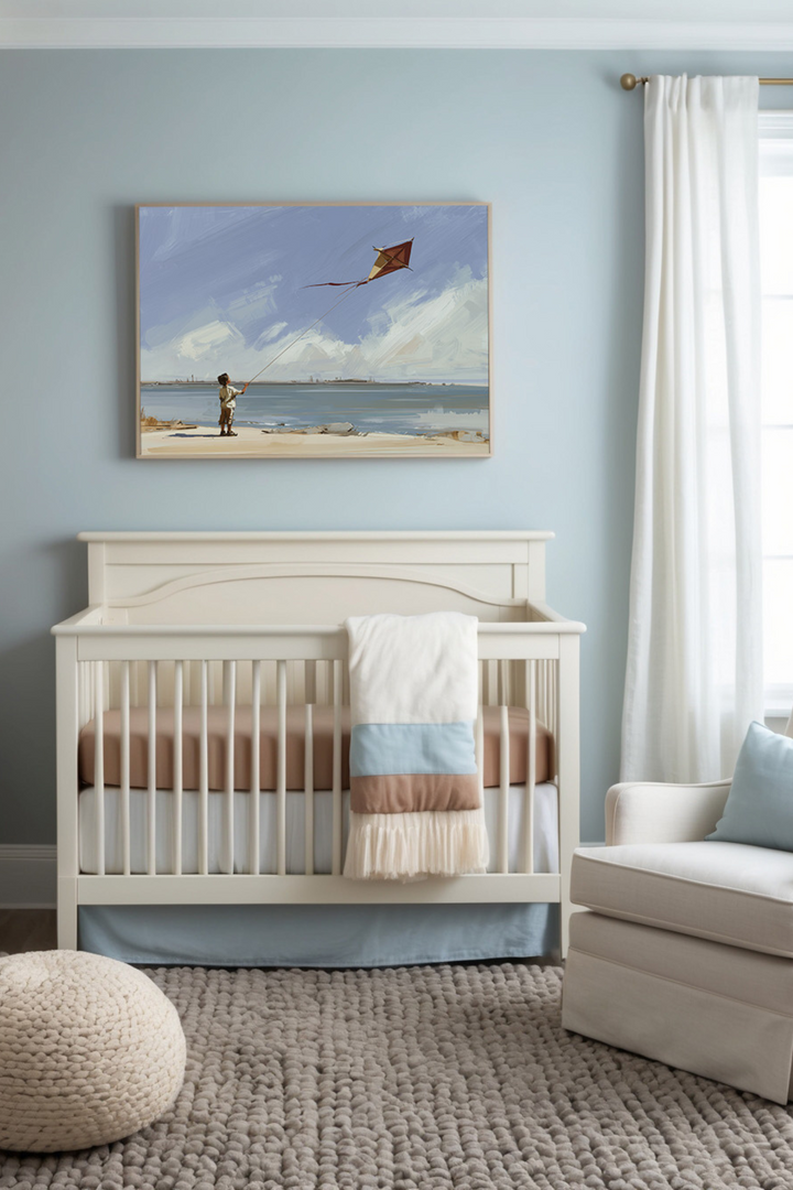 Calming nursery featuring soft neutral tones with a cream crib, pastel bedding, and a plush textured rug. A framed painting above the crib depicts a serene beach scene with a child flying a kite, complementing the room's tranquil aesthetic.