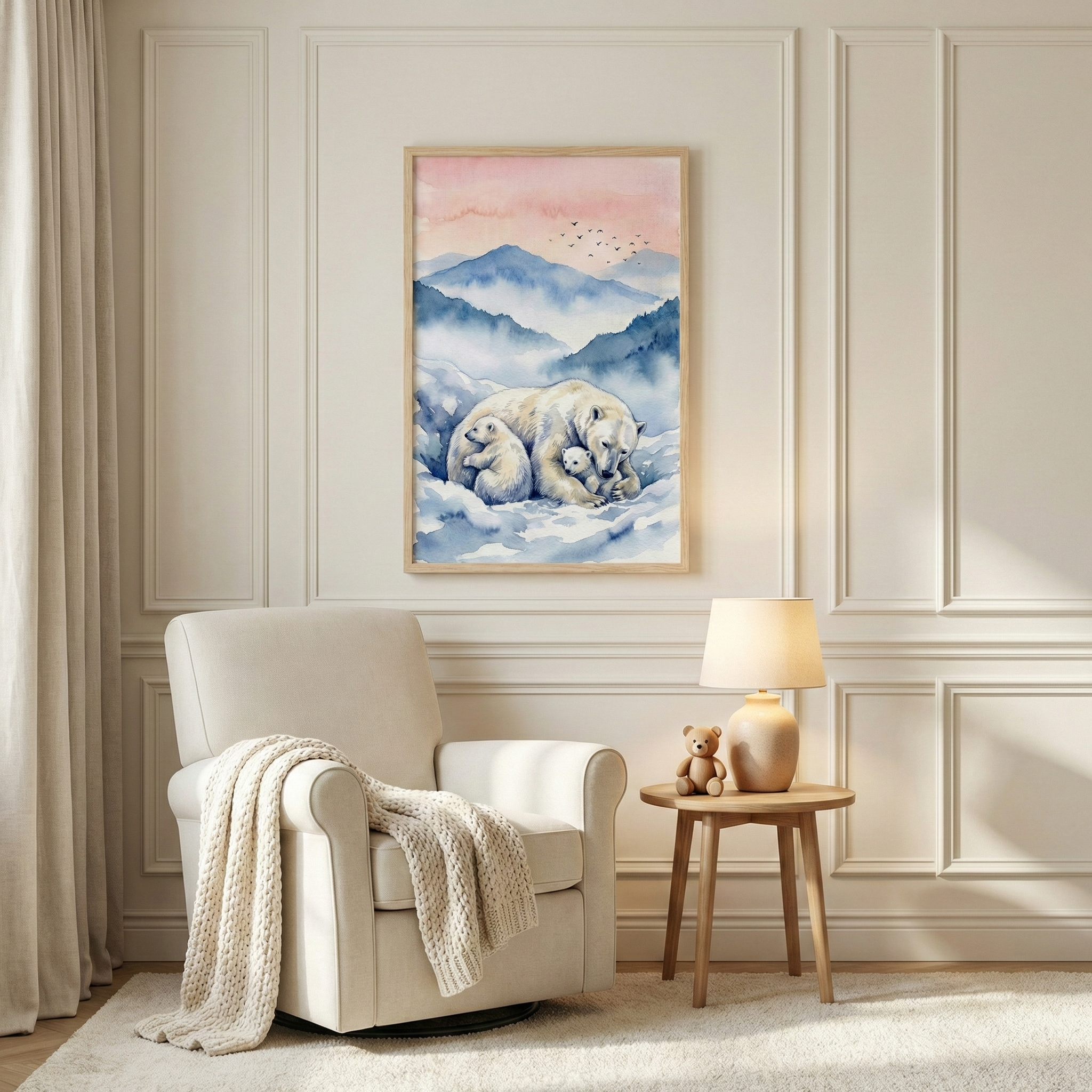 A serene nursery scene features a framed watercolor-style illustration of a mother polar bear and two cubs in a snowy mountain landscape under a soft pink sky. The artwork is mounted on a white wainscoted wall above a plush white armchair draped with a chunky knit beige throw. Beside the chair is a light wood side table holding a warm, glowing lamp and a small brown stuffed bear. The room is decorated in soft, neutral tones, creating a peaceful and cozy atmosphere.