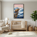 A cozy neutral nursery features a light wood crib with cream bedding and a textured knit blanket draped over the side. Above the crib hangs a framed watercolor print of a brown bear standing on a cliff overlooking misty blue mountains and pine trees at sunrise with birds in the sky, creating a calm woodland focal point. A beige rocking chair, round side table with lamp, woven basket of teddy bears, tall leafy plant, and soft white rug complete the warm minimalist space.