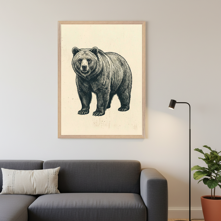Modern living room with a dark gray sectional sofa and a light pillow. A large framed black and white line art drawing of a grizzly bear hangs above the sofa. A black floor lamp stands to its right, and a potted plant is further right on the floor.