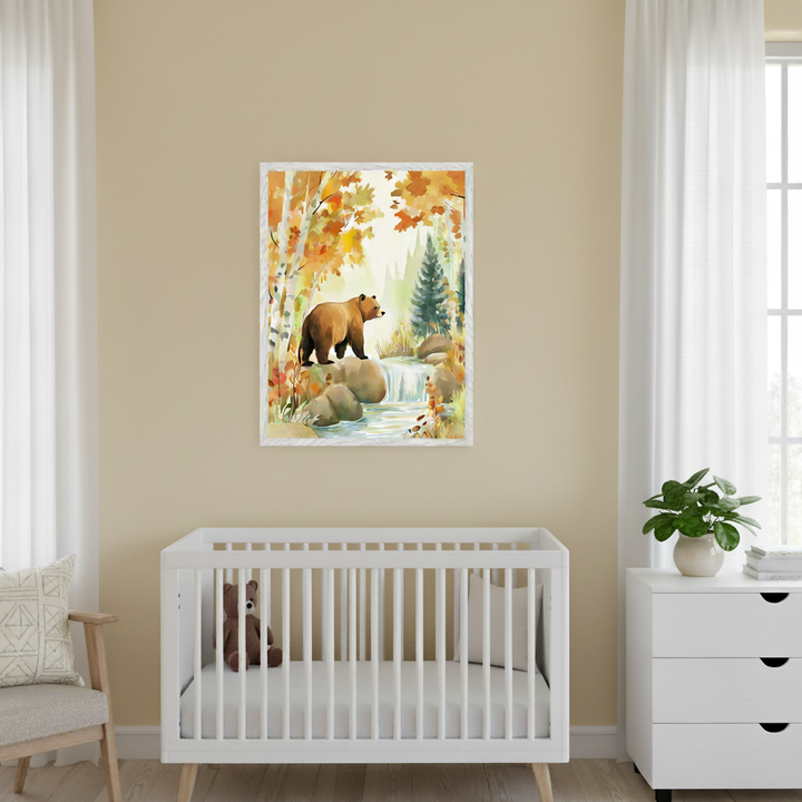Bright nursery room with a white crib, white dresser, and armchair. A framed watercolor art print of a brown bear by a waterfall in an autumn forest with orange trees hangs centered above the crib.