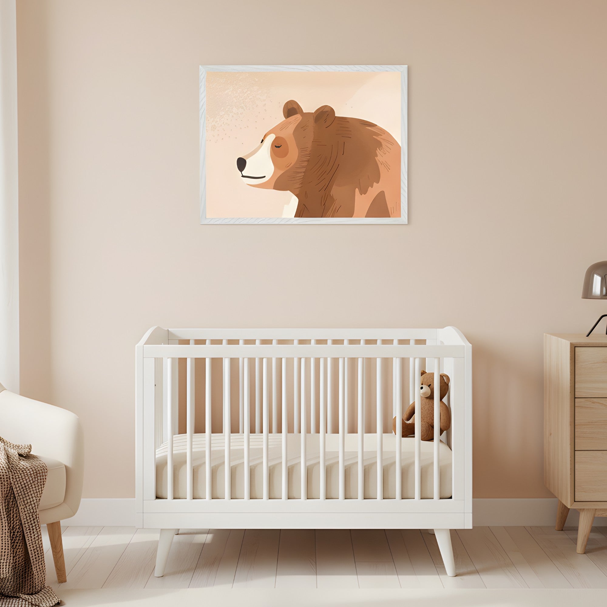 Modern nursery with a white crib. A framed illustration of a sleeping brown bear hangs above the crib on a light beige wall. A cream armchair is to the left, and a wooden dresser to the right.