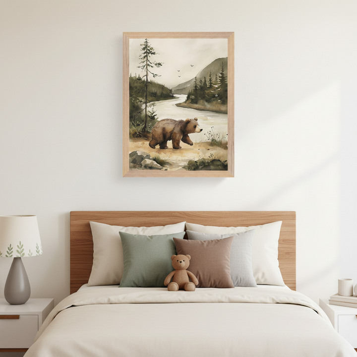 Kid's bedroom with a wooden bed, light bedding, and a teddy bear. A framed watercolor painting of a brown bear walking by a river with trees and mountains hangs above the bed, off-center to the right. A lamp is on the left nightstand.