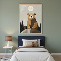 Kid's bedroom featuring a navy blue single bed against a sage green wall. Above the bed, a large framed illustration shows a brown bear sitting on a rock under a full moon and starry sky, with dark pine trees. A white nightstand with a brown lamp sits beside the bed.