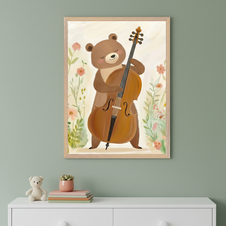 An illustration of a smiling cartoon bear gently playing a large cello surrounded by soft pastel flowers, set against a light background. The artwork hangs above a white dresser with a teddy bear, stacked books, and a small potted plant.