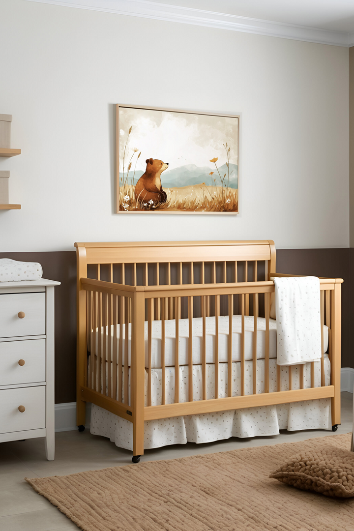 A calming nursery featuring a natural wood crib accented by white bedding with subtle patterns. Above it hangs a tranquil illustration of a bear sitting peacefully in a meadow, enhancing the room's gentle, nature-inspired decor.