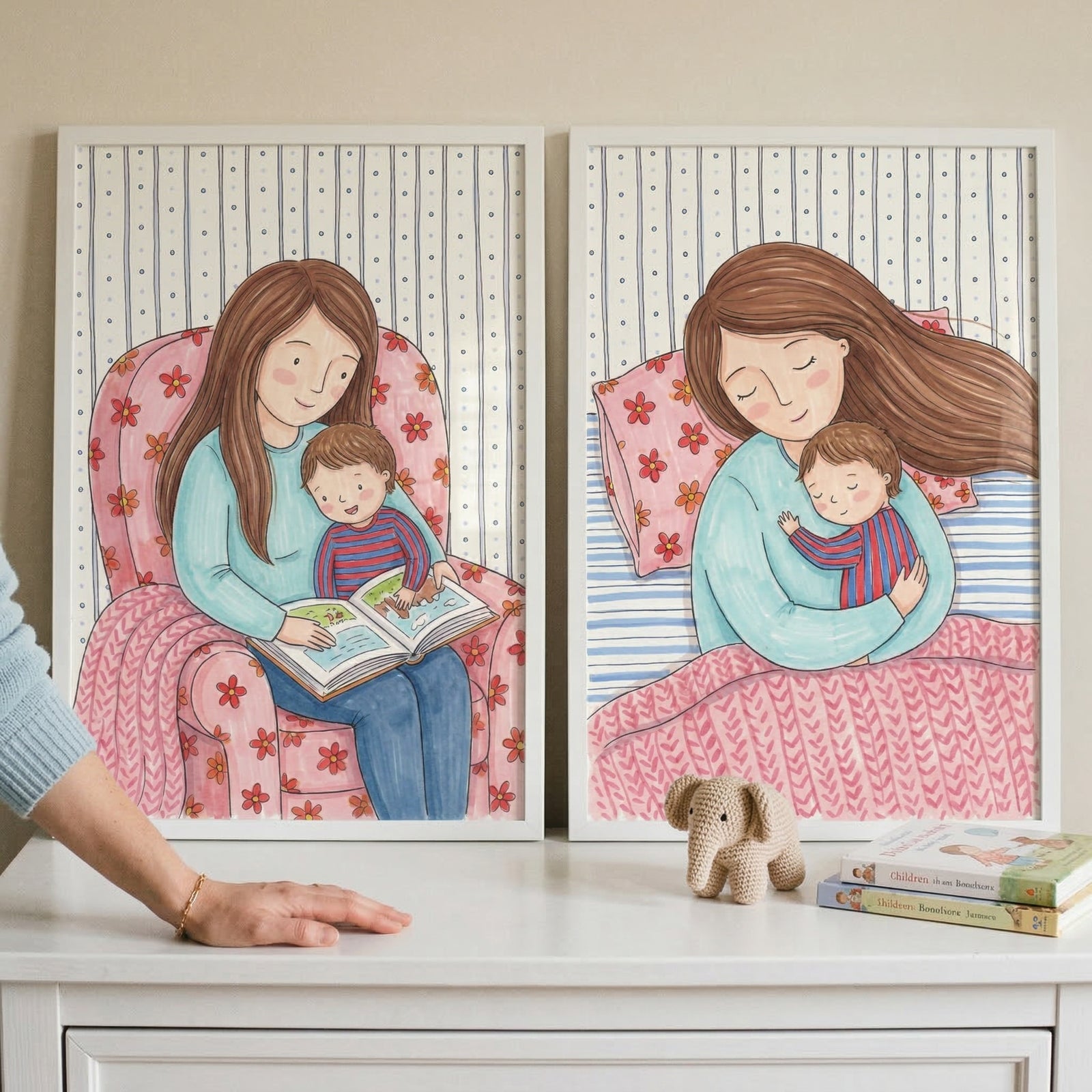 This image features two framed illustrations side-by-side on a white surface, depicting tender moments between a mother and her young child.

The illustration on the left shows a woman with long brown hair wearing a light blue long-sleeved shirt and blue pants. She is sitting in a large pink armchair adorned with a red floral pattern. A small child with short brown hair, dressed in a red and blue striped shirt, sits on her lap. Together, they are engaged in reading a book, which they both hold open. 