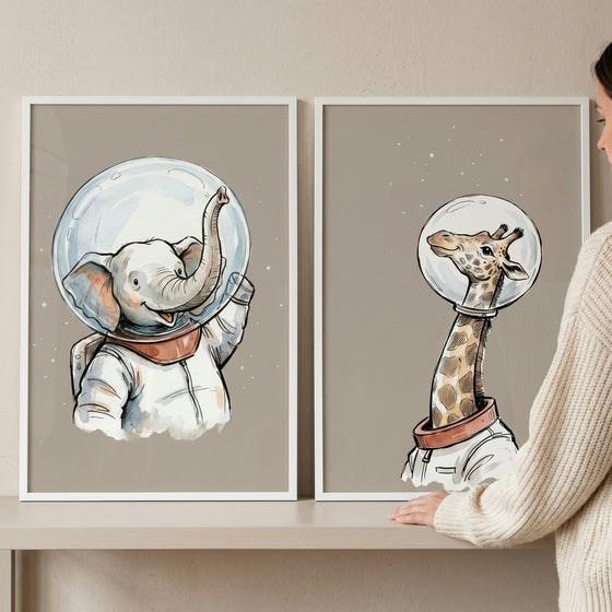 Beige cosmic astronaut animal wall art set of 2 showing an elephant and giraffe wearing space suits and bubble helmets.