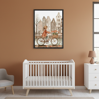 Modern nursery with a white crib, white dresser, and gray armchair. A framed watercolor painting of a girl on a bicycle with tulips, riding by a canal with European-style buildings, hangs centered above the crib.