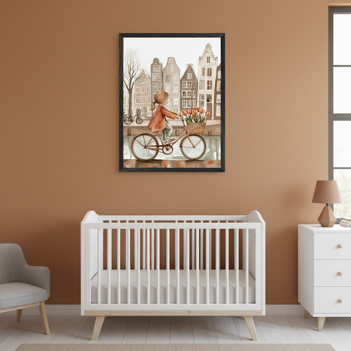 Modern nursery with a white crib, white dresser, and gray armchair. A framed watercolor painting of a girl on a bicycle with tulips, riding by a canal with European-style buildings, hangs centered above the crib.