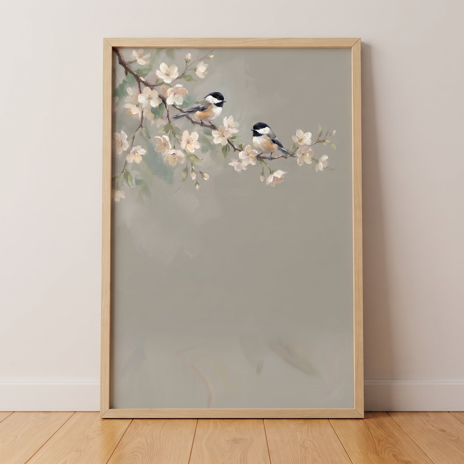 Two birds rest on a flowering branch in this framed black capped chickadee floral wall art against a neutral wall.