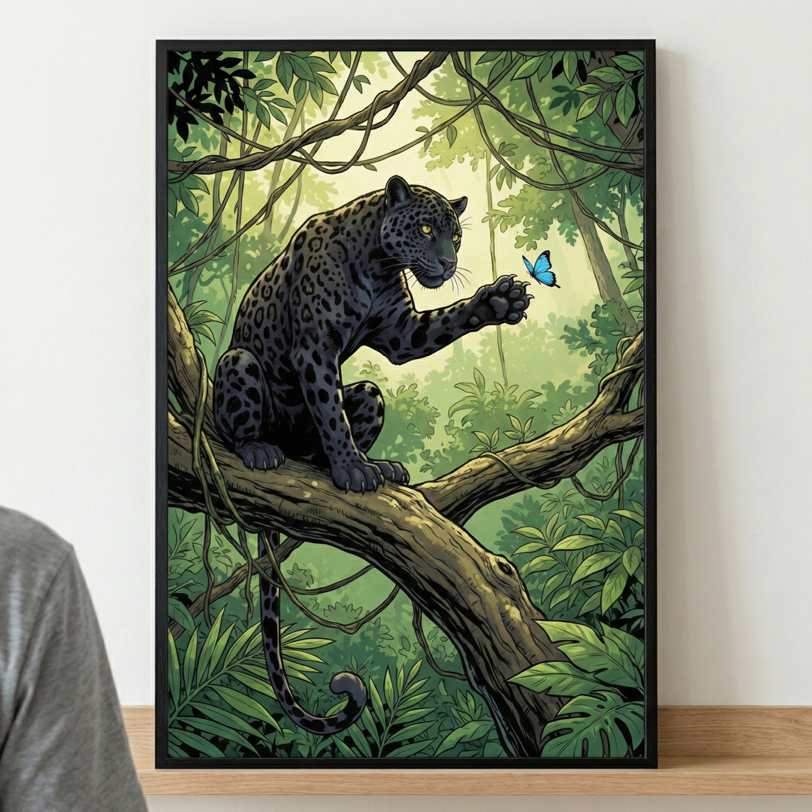 A framed illustration of a black leopard with dark spots, perched on a large tree branch in a lush, green jungle. The leopard is reaching a paw out toward a small blue butterfly in the air. Sunlight filters through the dense canopy of leaves and vines in the background. The vertical artwork is encased in a thin black frame and sits on a wooden shelf.