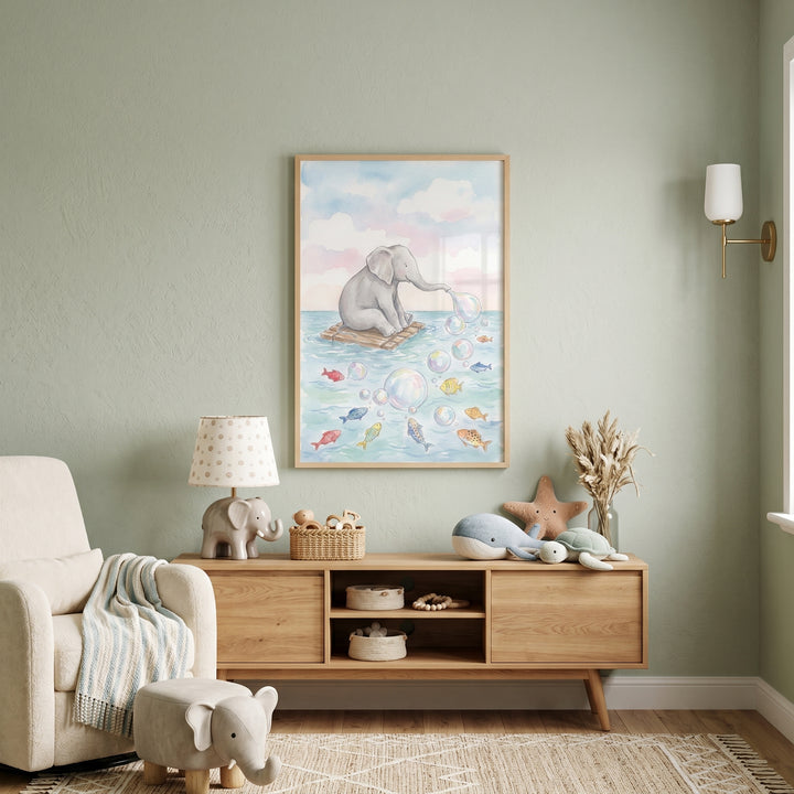 Blowing bubbles baby elephant wall art in a sage nursery above a wooden cabinet with plush toys and a cozy armchair.